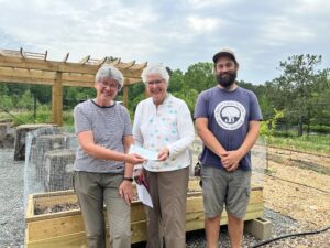 Three people smiling in front of a pergola
