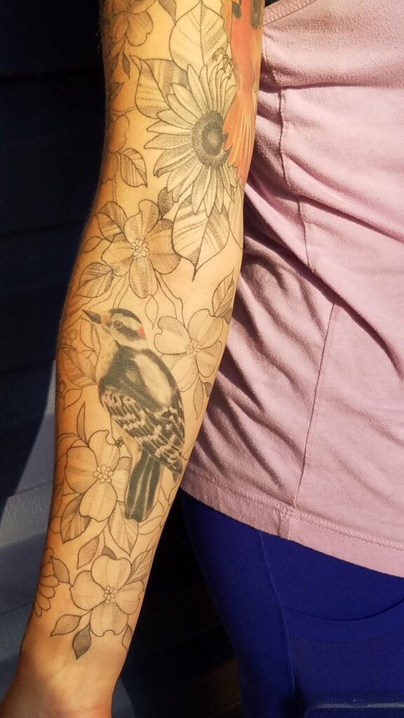 Deanna's arm tattoos, which include a woodpecker, dogwood blooms and other flowers